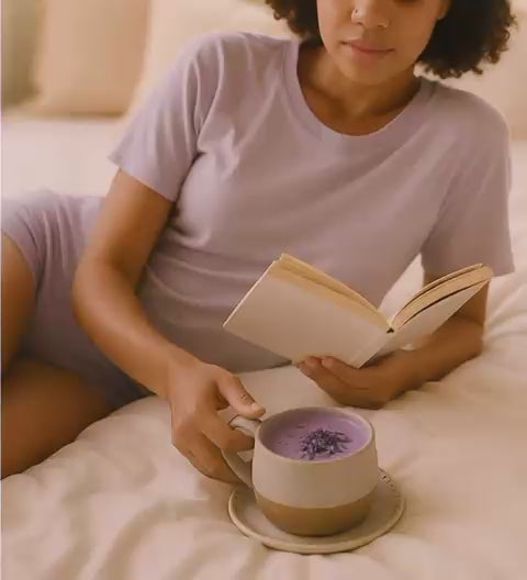 Woman lying on bed sipping Dreamy Soothe lavender taro botanical latte
